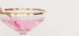 Coupe de champagne rosé avec une paille à rayures rose et blanche