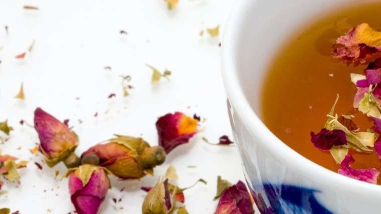 bol de thé avec des boutons de roses à la surface du breuvage