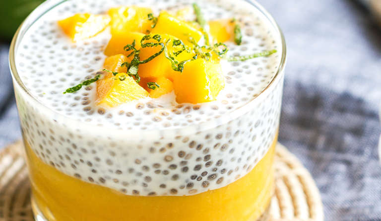 chia pudding à la mangue servi dans un verre à tapas décoré de cubes de mangue
